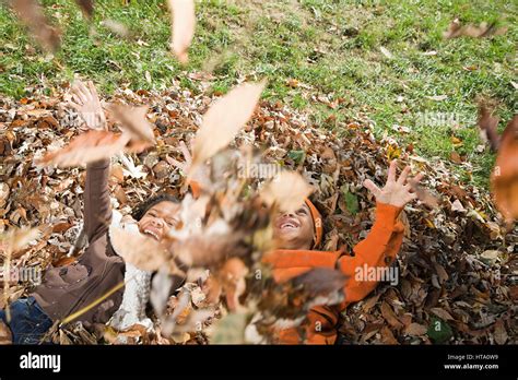 Kids playing in leaves Stock Photo - Alamy