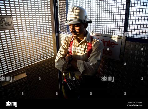 A worker rides the caged elevator on the outside of the Burj Khalifa to ...