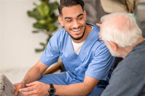 Young Caretaker Smiling at an Elderly Person Sitting beside Him Stock Image - Image of caretaker ...