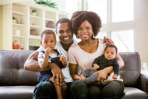 Smiling Black family posing on sofa - Stock Photo - Dissolve