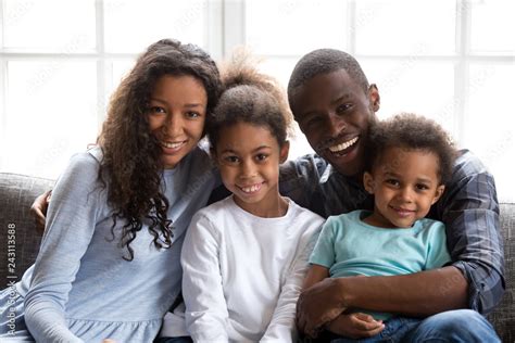 Happy black family of four dad mom and little son daughter, loving african mother father embrace ...