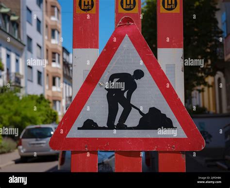 Man At Work Sign On Road. Construction warning sign on blur traffic road with colorful bokeh ...