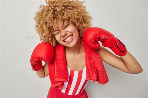 Positive female boxer with curly hair wears boxing gloves ready for ...