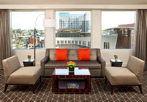 a living room with couches, chairs and a coffee table in front of large windows