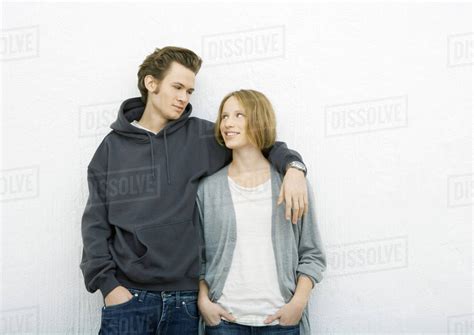 Young couple, man with arm around woman's shoulder, woman looking up at him - Stock Photo - Dissolve