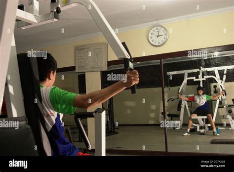 A young badminton athlete doing gym exercise in front of a large mirror ...