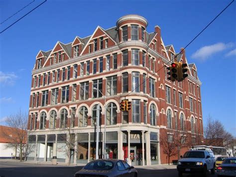 an old red brick building on the corner of a street with cars parked in front