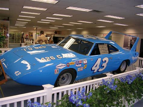 a blue race car is on display in a museum with other cars and flowers ...