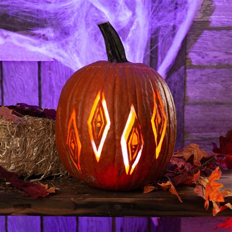 a carved pumpkin sitting on top of hay next to fall leaves and purple lights in the background