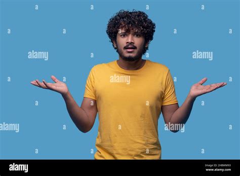 Puzzled guy with curly hair showing his uncertaintyPuzzled guy with ...