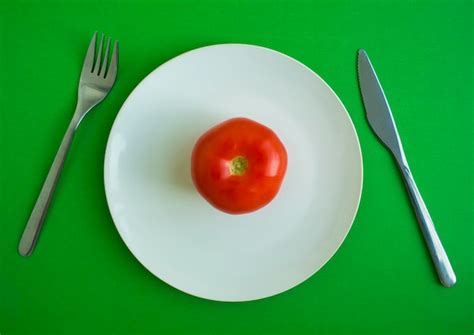 Premium Photo | Tomato in a plate fork and knife