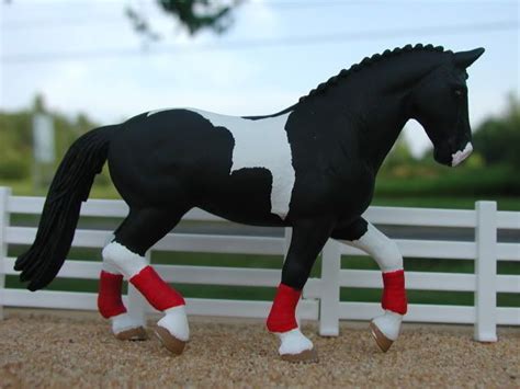 a black and white horse with red socks on it's legs is standing in ...