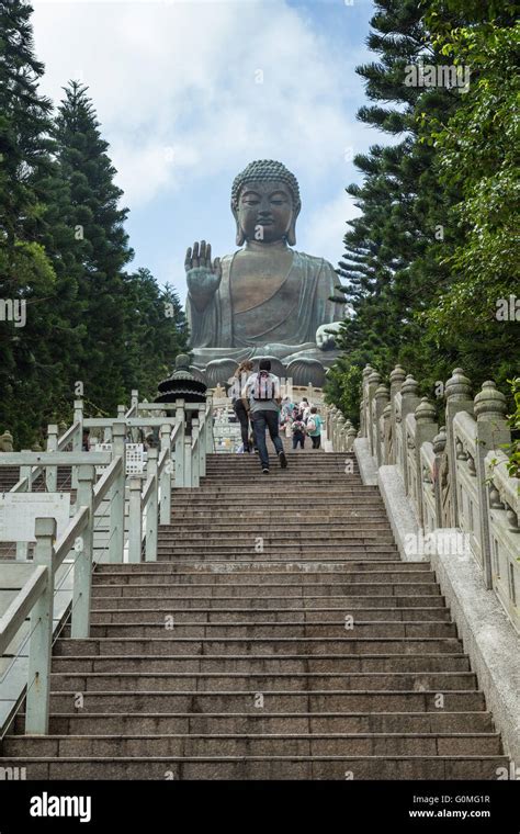 Handful of people climbing long flight of stairs to the Tian Tan Buddha or Big Buddha statue in ...