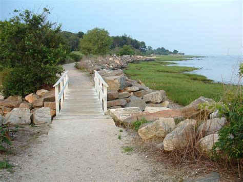 there is a wooden bridge that leads to the water and rocks on both ...