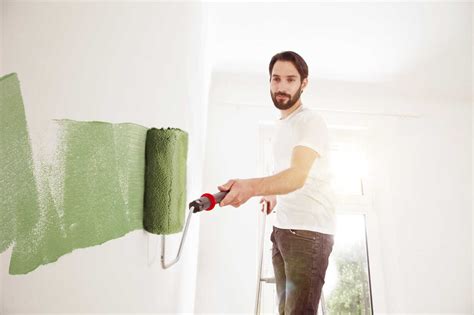 Young man painting a wall green stock photo