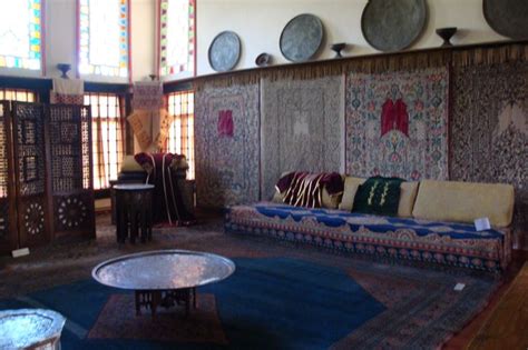 a living room filled with lots of furniture next to large stained glass windows on the wall