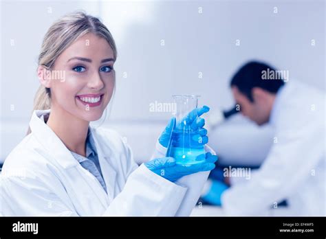 Science student holding blue chemical in beaker Stock Photo - Alamy