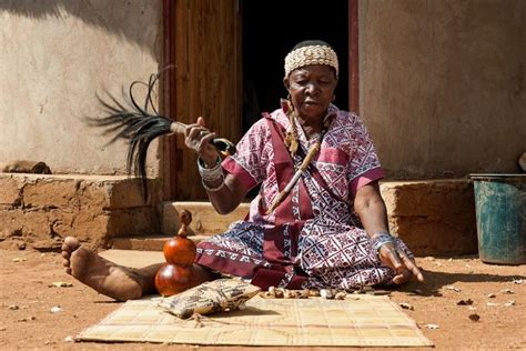 an old woman sitting on the ground with a bird in her hand and other ...