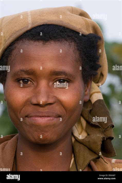 Beautiful Rwandan woman in sight of active Virunga volcanic mountains near Lake Burera Central ...