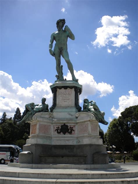 a statue is shown in front of a blue sky with white clouds and some trees