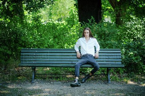 Portrait confident young man sitting on park bench - Stock Photo - Dissolve