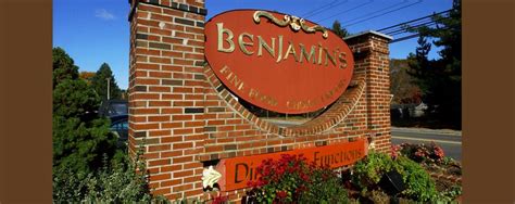 a brick sign that reads benawans on it's side next to flowers and trees