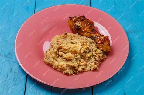 Premium Photo | Couscous in sauce and spices with grilled chicken drumstick on a plate on a blue ...
