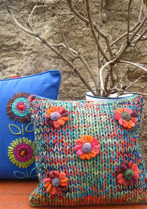 two colorful pillows sitting next to each other on a wooden table with a tree in the background