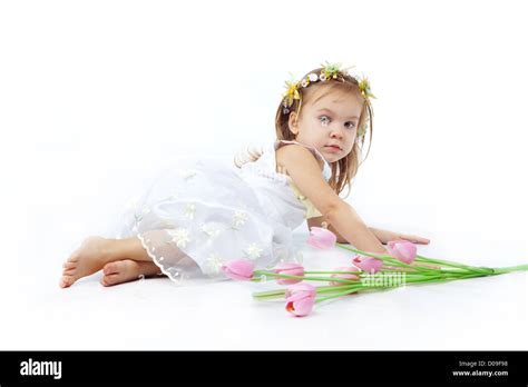 Beautiful little girl in dress lying near tulips on white background Stock Photo - Alamy