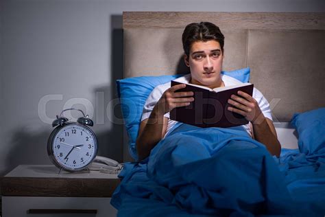 Young man reading book in bed | Stock image | Colourbox