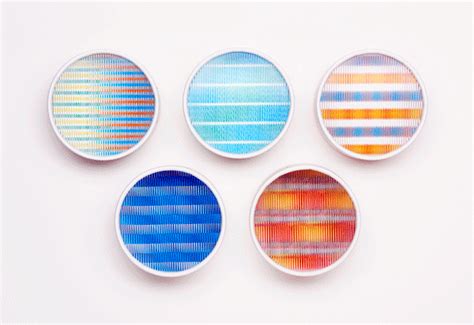 four different colored plates sitting on top of a white table next to an orange and blue striped ...