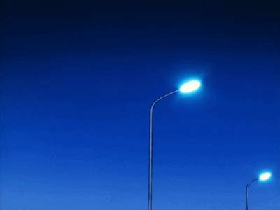 two street lamps on the side of an empty road at night with blue sky in ...