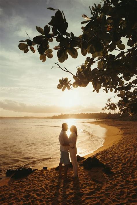 Embracing Couple Stand on Sandy Beach at Sunset · Free Stock Photo