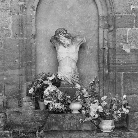 Premium Photo | A statue of jesus is surrounded by flowers and a vase ...