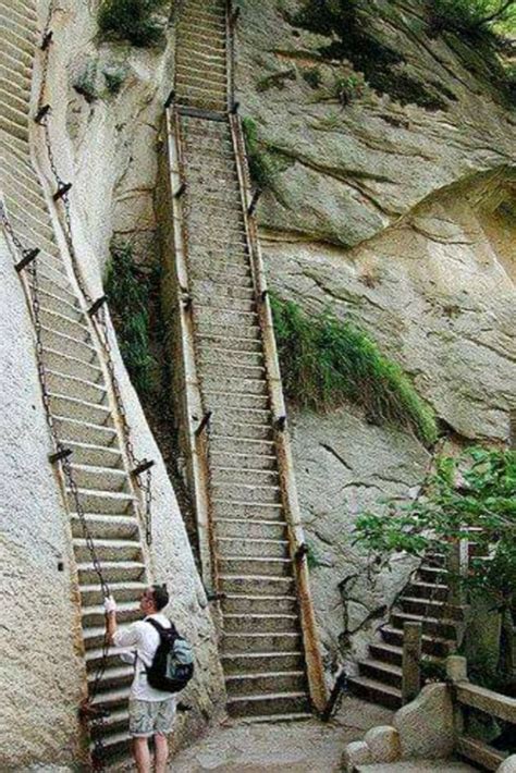 two people are climbing up some stairs in the mountains, one is carrying a backpack