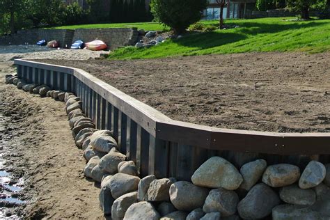 Contractor building a steel seawall bulkhead for lake property | Landscaping on a hill ...