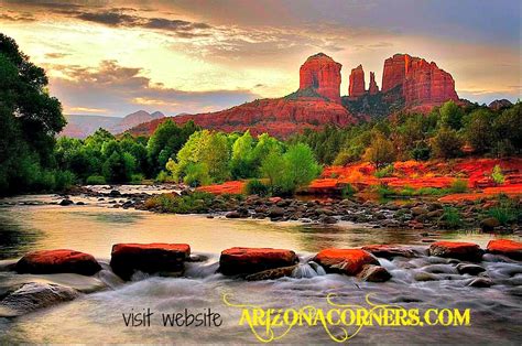 a river running through a lush green forest next to tall red rock formations in the distance