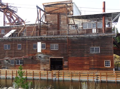 an old wooden building next to a body of water with a crane in the background