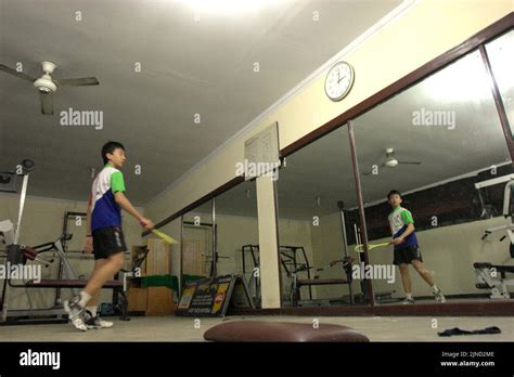 A young badminton athlete is practising various strokes in front of a ...