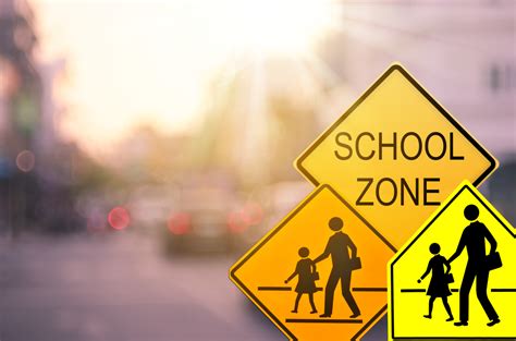 School zone warning sign on blur traffic road with colorful bokeh light abstract background ...