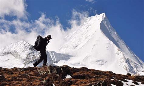 a man standing on top of a snow covered mountain next to a tall white peak