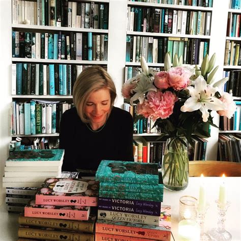 a woman sitting at a table in front of a stack of books with pink flowers