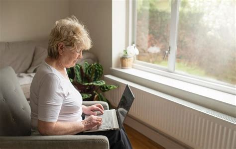 Premium Photo | Mature senior elderly woman sitting in a chair typing on a laptop