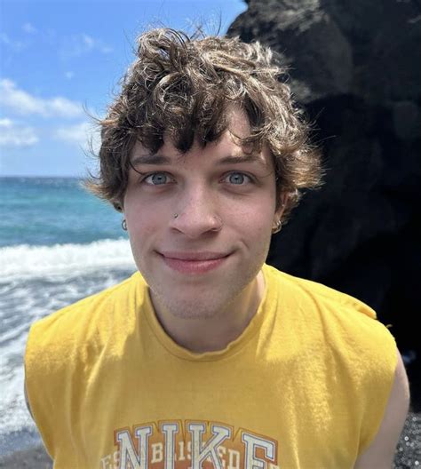 a young man standing on top of a beach next to the ocean