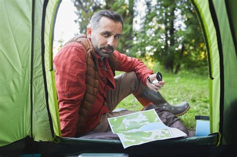 Premium Photo | From inside shot of mature man sitting by tent during camping trip in forest ...