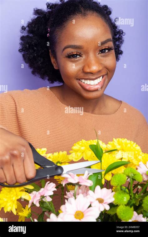 A young British Black woman holding a pair of scissors over flowers ...