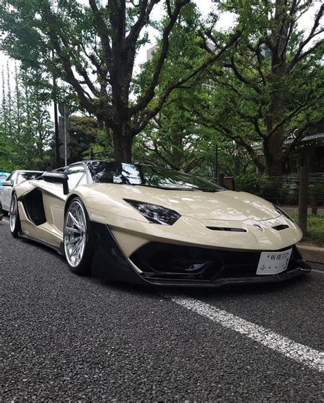 a white and black sports car is parked on the side of the road in front ...