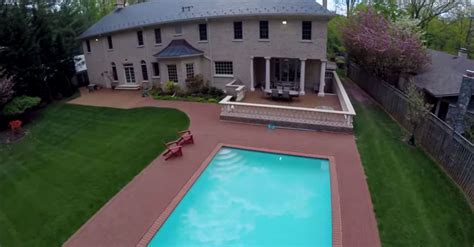 an aerial view of a large house with a pool in the yard and patio furniture