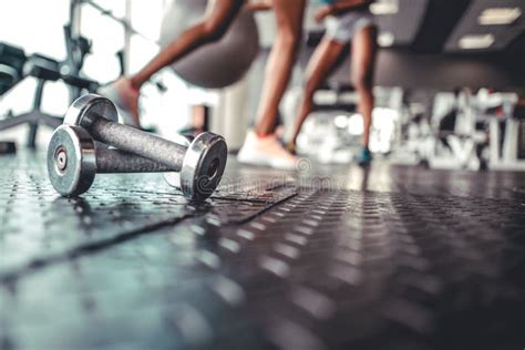 Dumbbell on a Flor in Fitness Gym with Legs in Background Stock Photo - Image of barbell ...