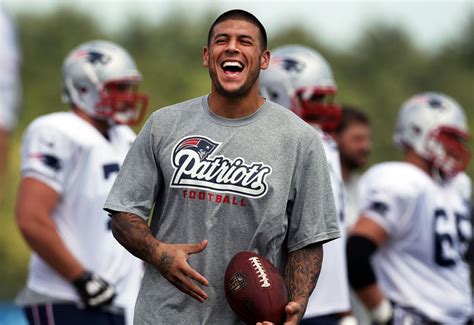 A smiling Aaron Hernandez stands on the field, football in hand, with his New England Patriots ...